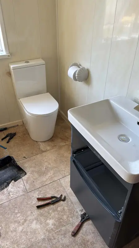 Bathroom job with a toilet and vanity basin unit, tools still on the floor